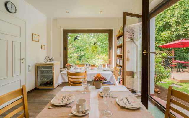 Gedeckte Frühstückstische im Frühstückraum, Blick in den Garten, Hotel Haus Nussbaum in Ratingen