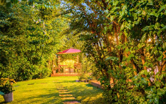 Abendstimmung im Garten, Tische, Stühle und Sonnenschirme im Garten des Hotels Nussbaum in Ratingen