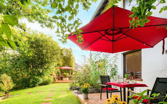 Tische, Stühle und Sonnenschirme im Garten des Hotels Nussbaum in Ratingen