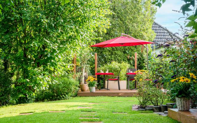 Tische, Stühle und Sonnenschirm im Garten des Hotels Nussbaum in Ratingen