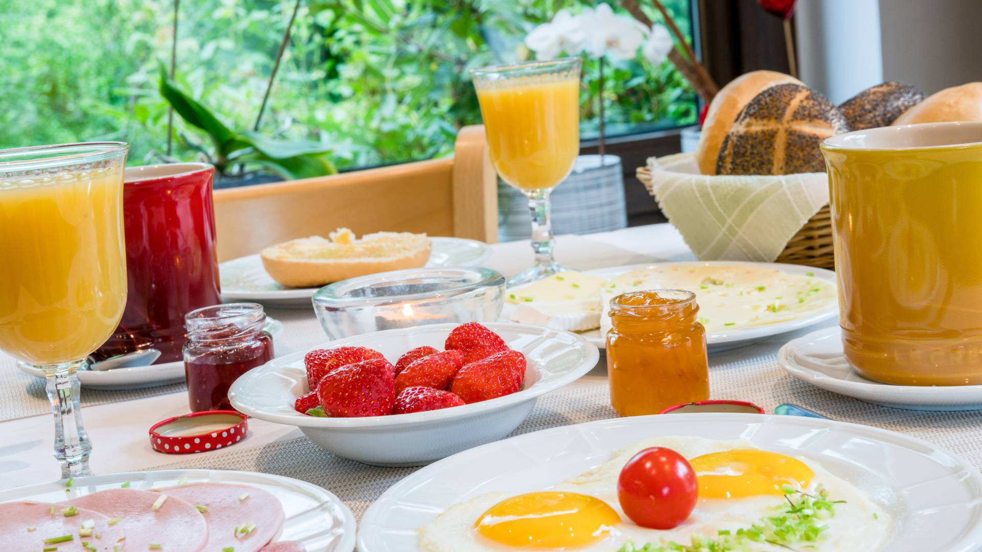 Gedeckte Frühstück mit Saft, Erdbeeren, Spiegelei, Wurst, Käse und Brötchen, Hotel Haus Nussbaum in Ratingen