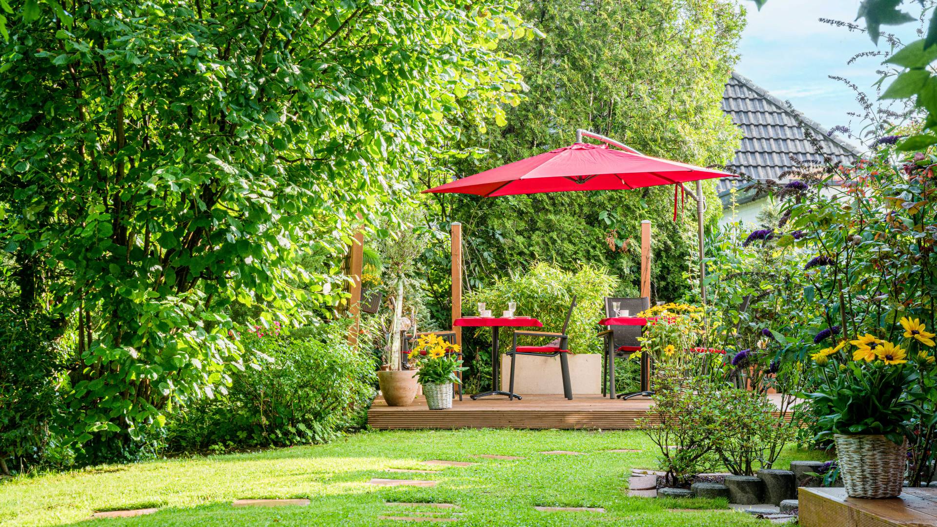 Tische, Stühle und Sonnenschirm im Garten des Hotels Nussbaum in Ratingen